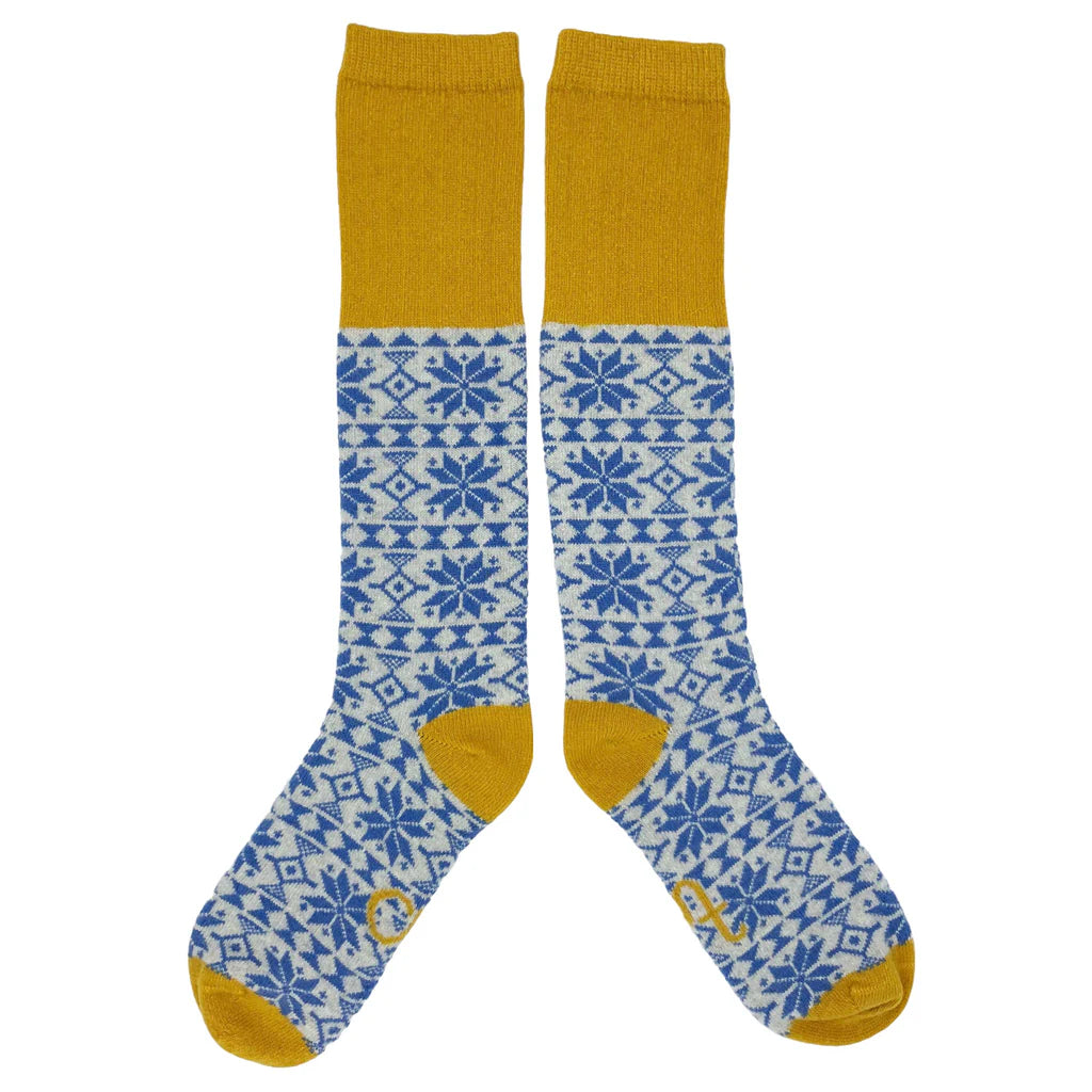 Pair of knee-high socks with a mustard yellow cuff and a blue and white snowflake pattern.