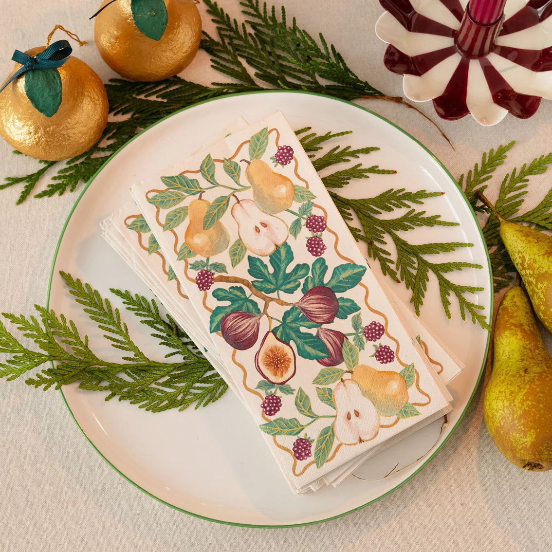 Decorative box with fruit design on a plate surrounded by pears and greenery