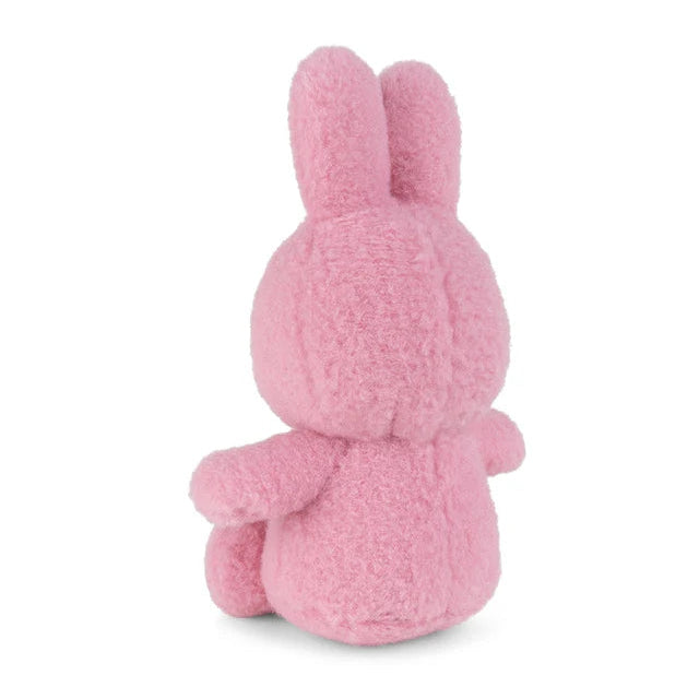 Pink plush bunny rabbit sitting, viewed from behind.  Soft, textured fur.