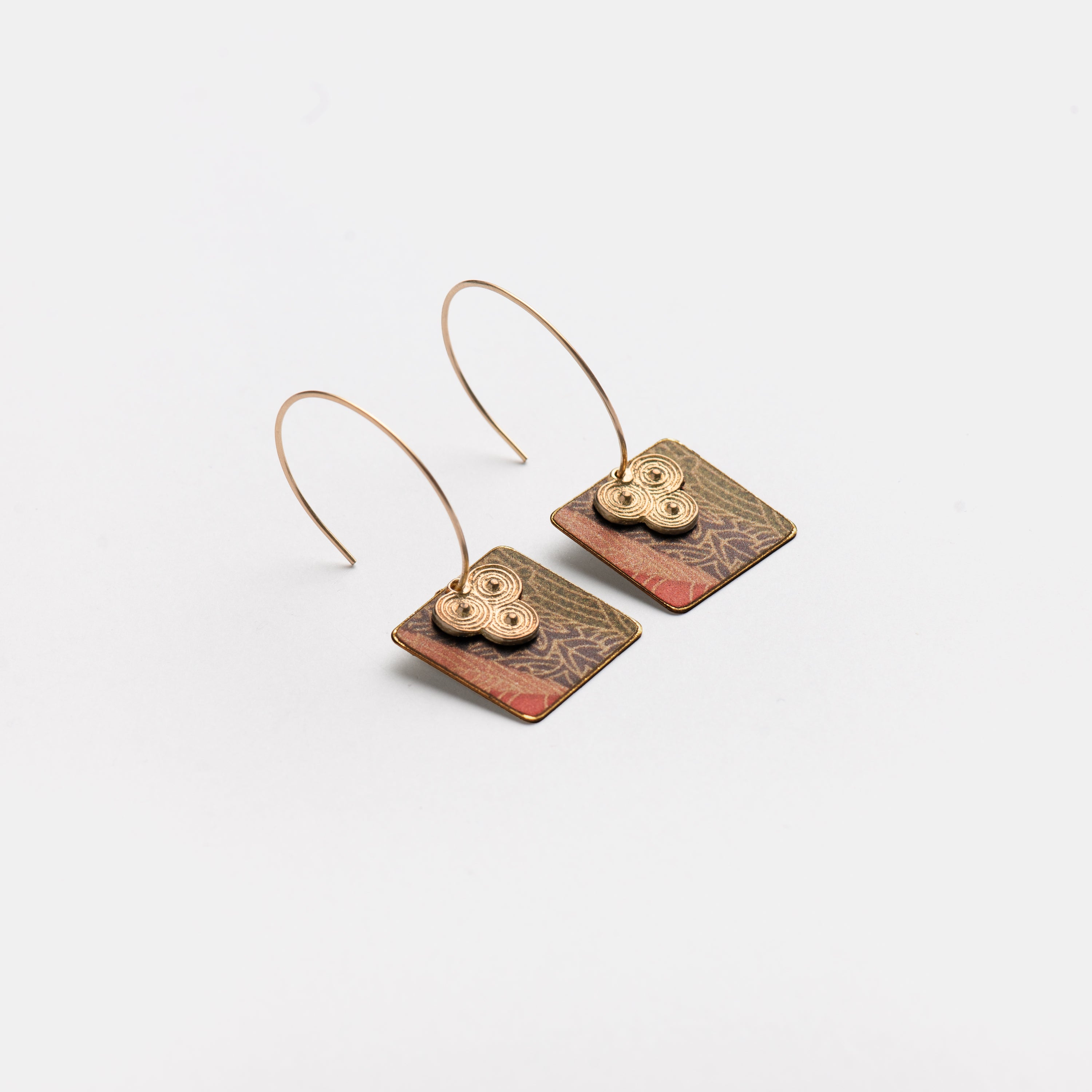 Pair of square earrings with gold wire hoops and patterned metal accents.