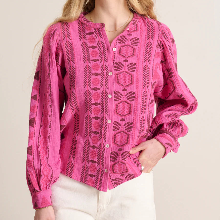 Woman wearing a pink patterned blouse against a plain background