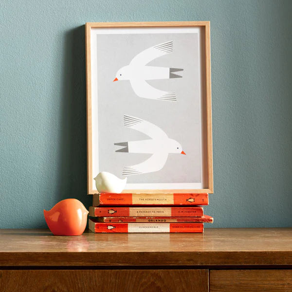 Framed print depicting two stylized white birds in flight against a light gray background.