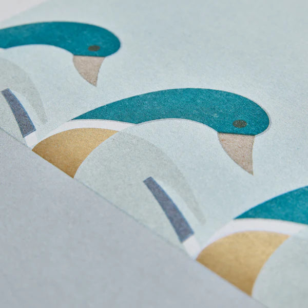 Teal stylized birds on a pale blue background, partially folded to show a light beige underside.