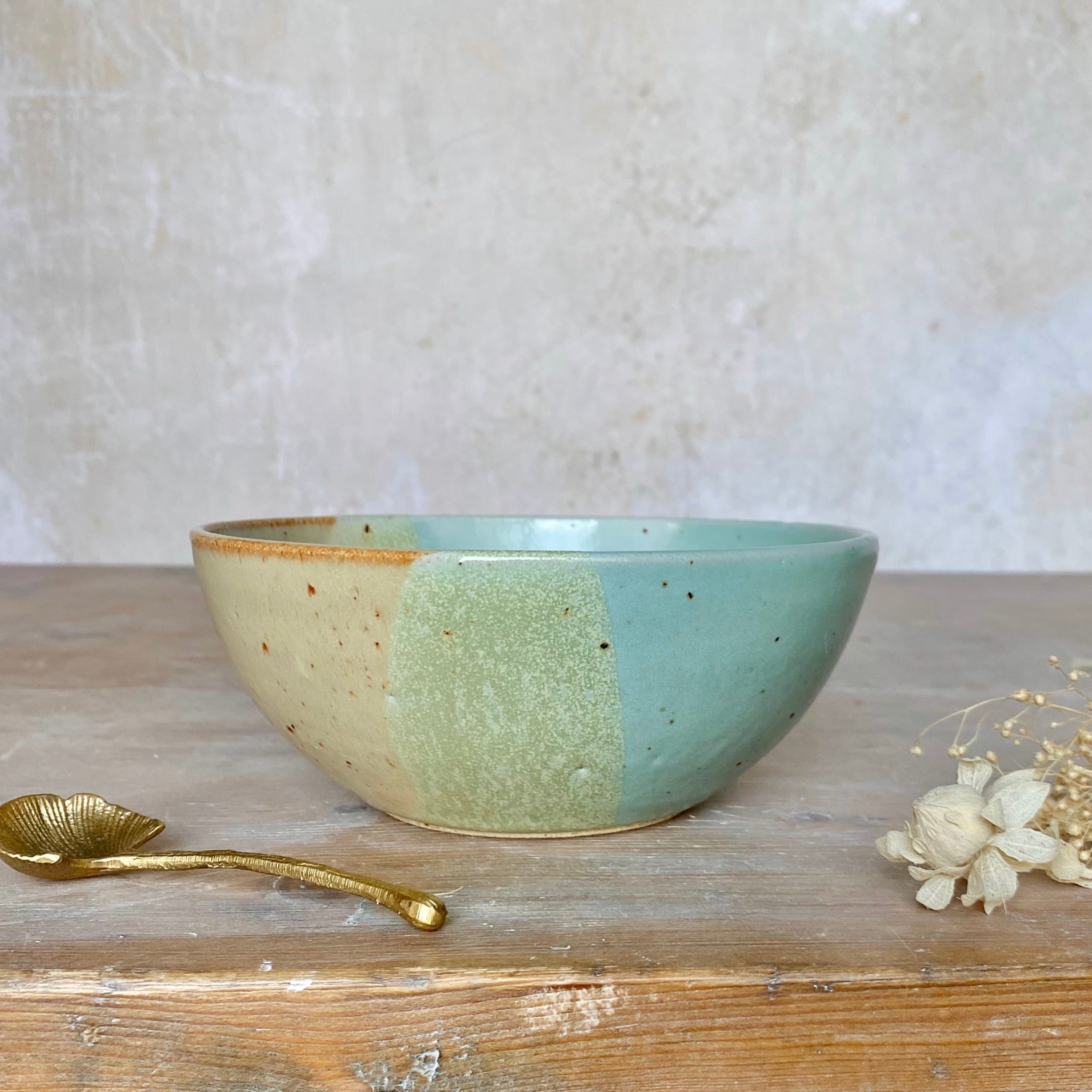 Handcrafted ceramic bowl with speckled, tri-color glaze in beige, sage green, and teal.
