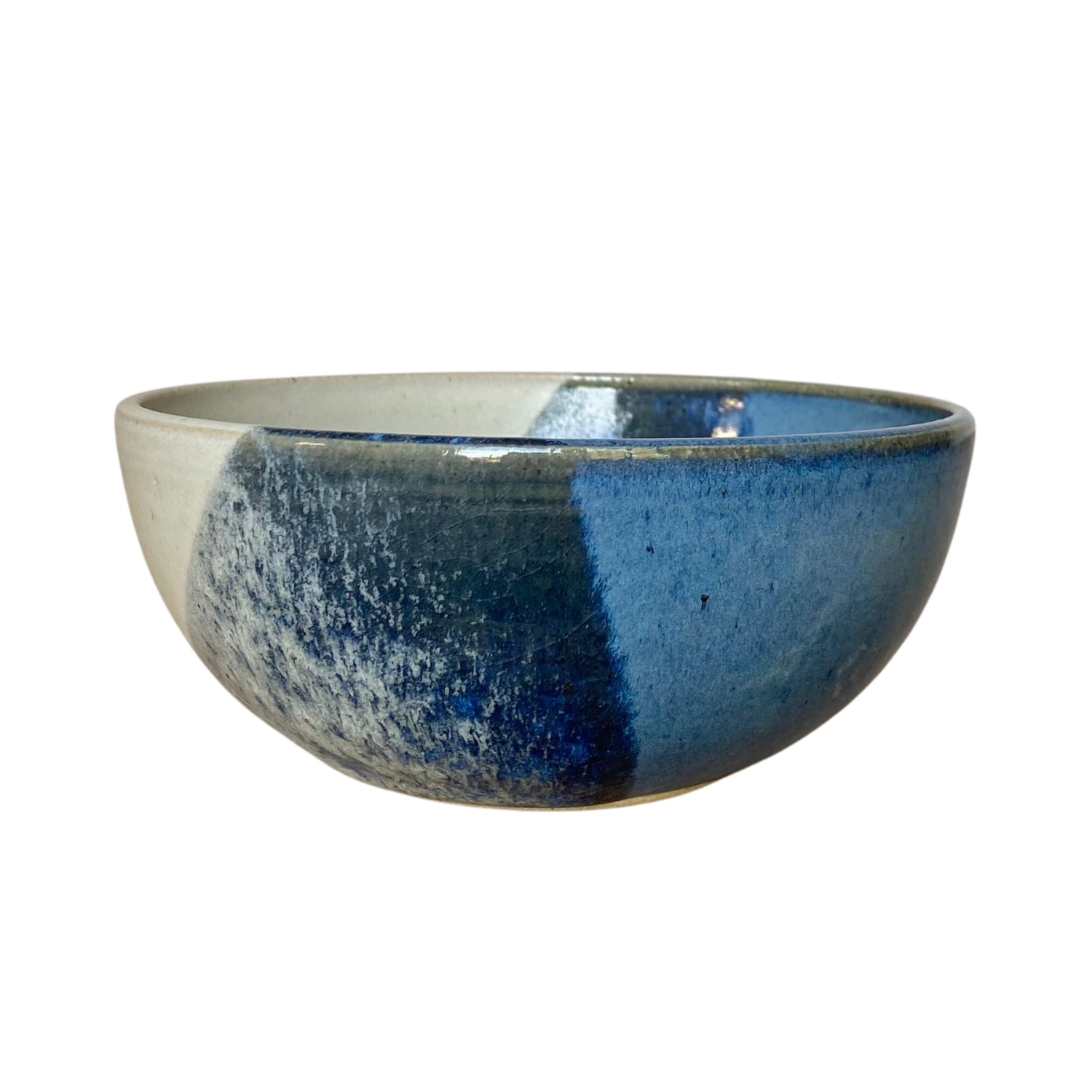Hand-thrown ceramic bowl with blue and off-white glaze, showing variations in color and texture.