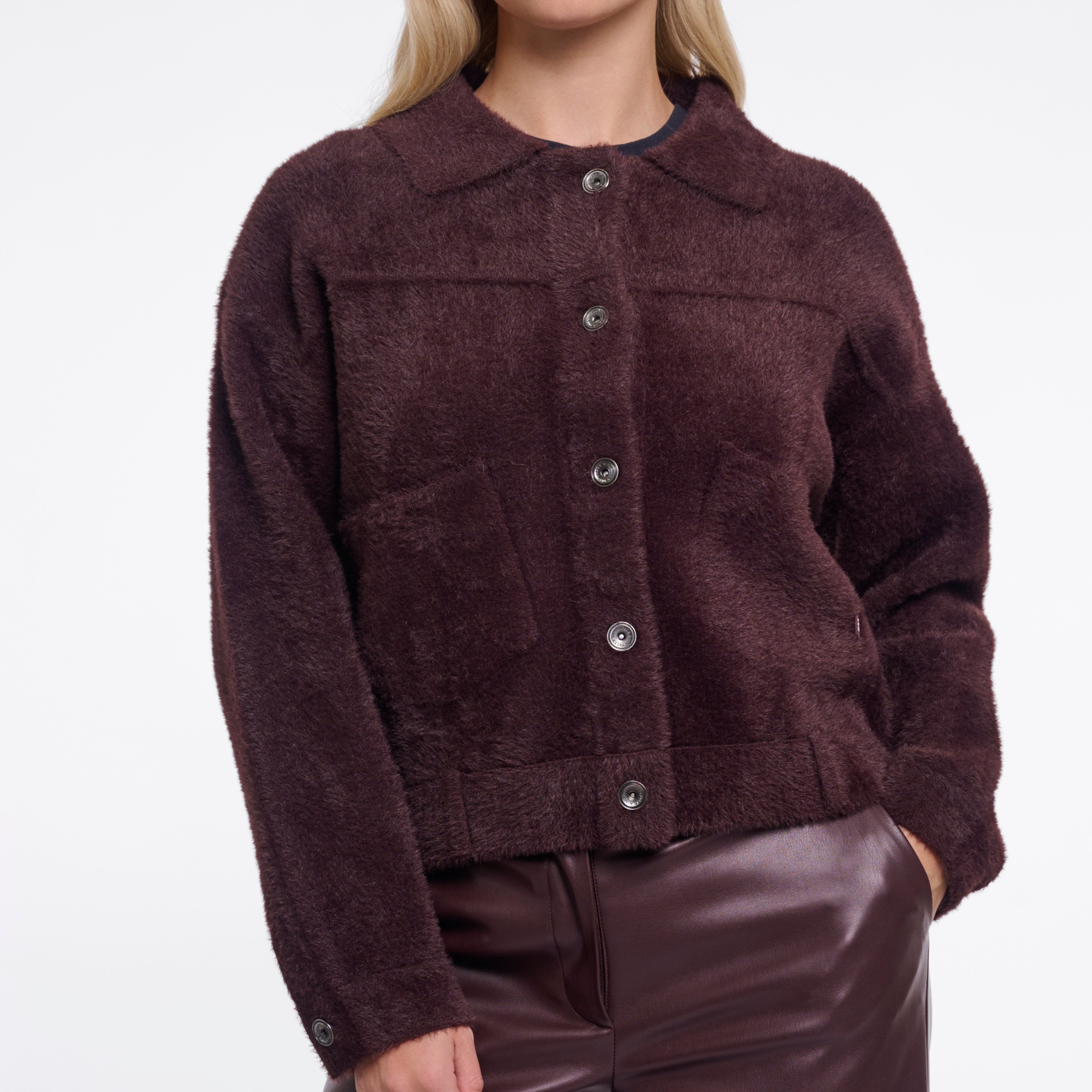 Woman wearing a brown jacket and pants on a white background