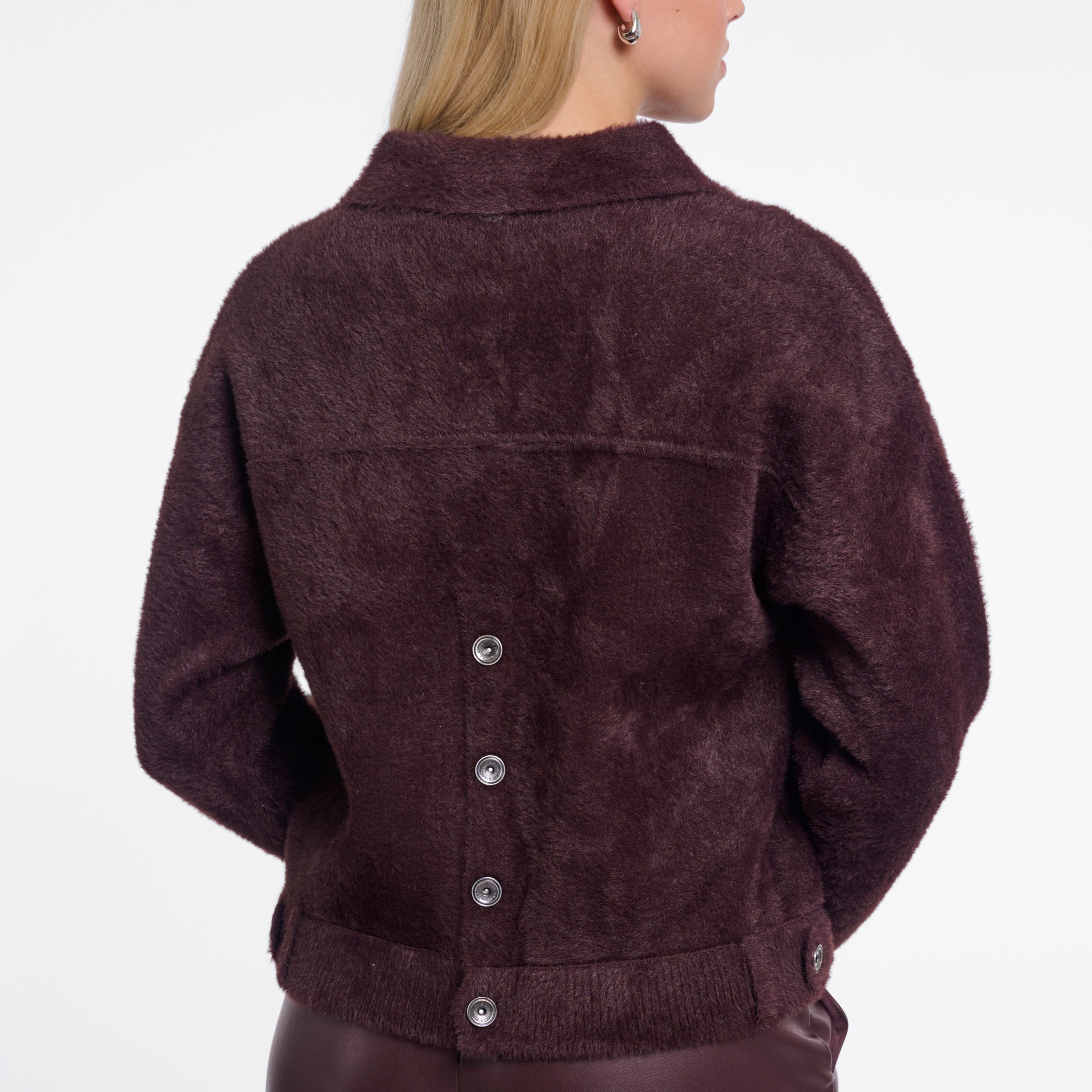 Woman wearing a brown suede jacket on a white background