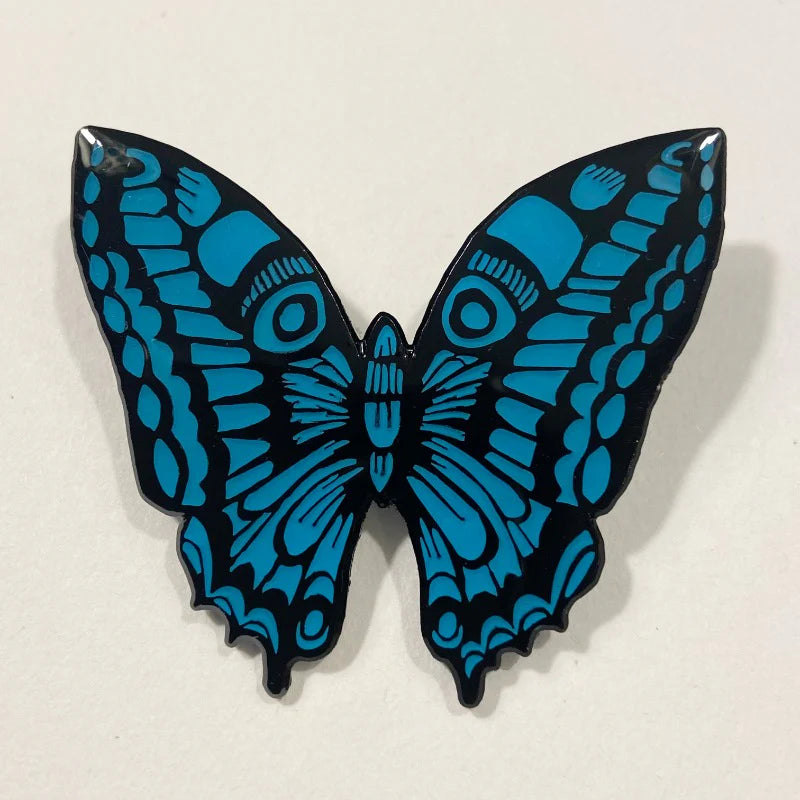 Teal and black enamel pin of a stylized butterfly with detailed wing patterns.