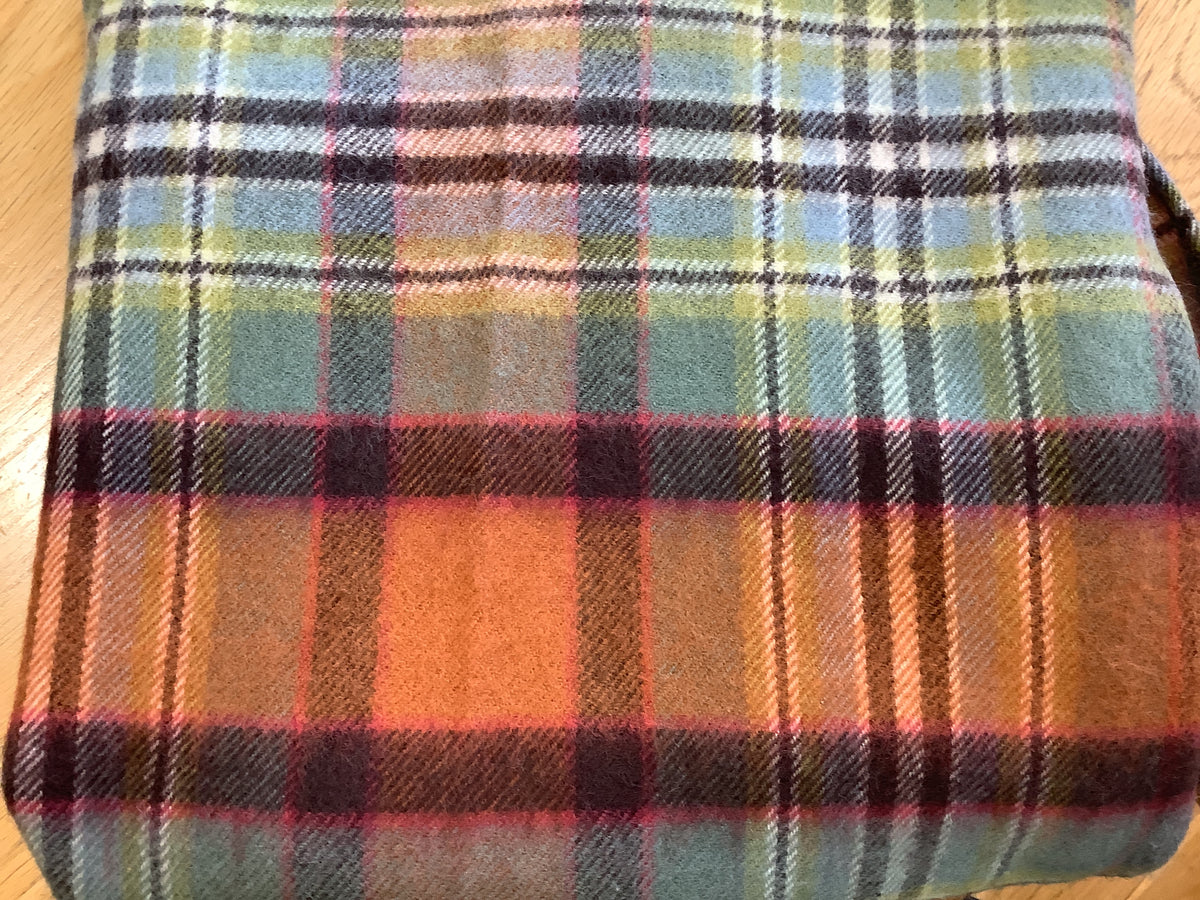 Folded woolen throw blanket with a multicolored plaid pattern in shades of orange, brown, green, and blue.