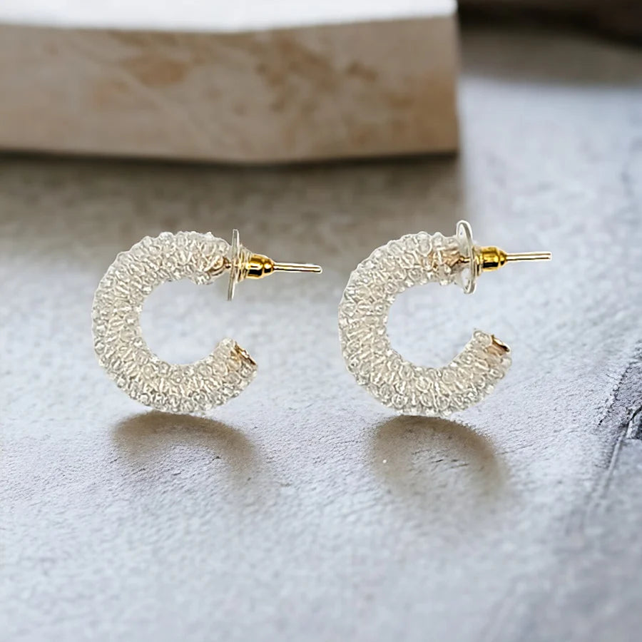 Gold hoop earrings on a textured surface