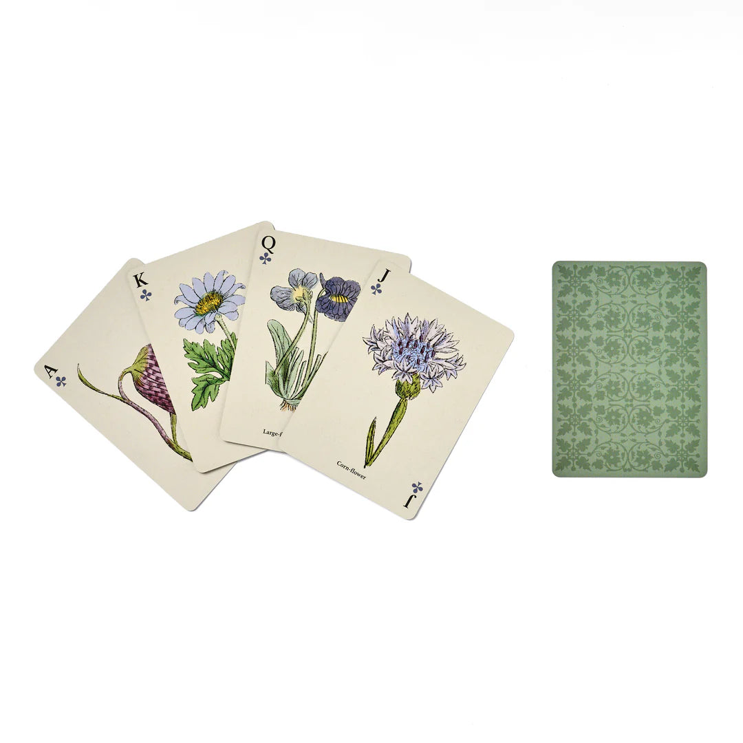 Set of playing cards with floral designs on beige cardstock, next to a green notebook.