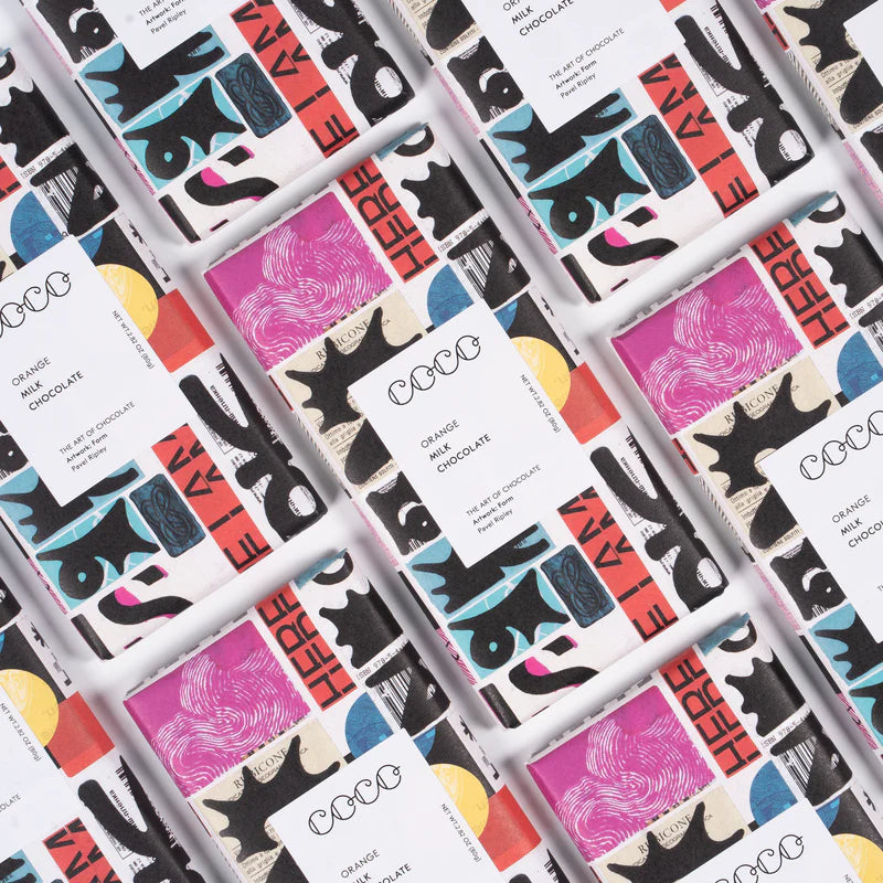 Several bars of Coco orange milk chocolate, each wrapped in white with a vibrant abstract design featuring black, pink, and