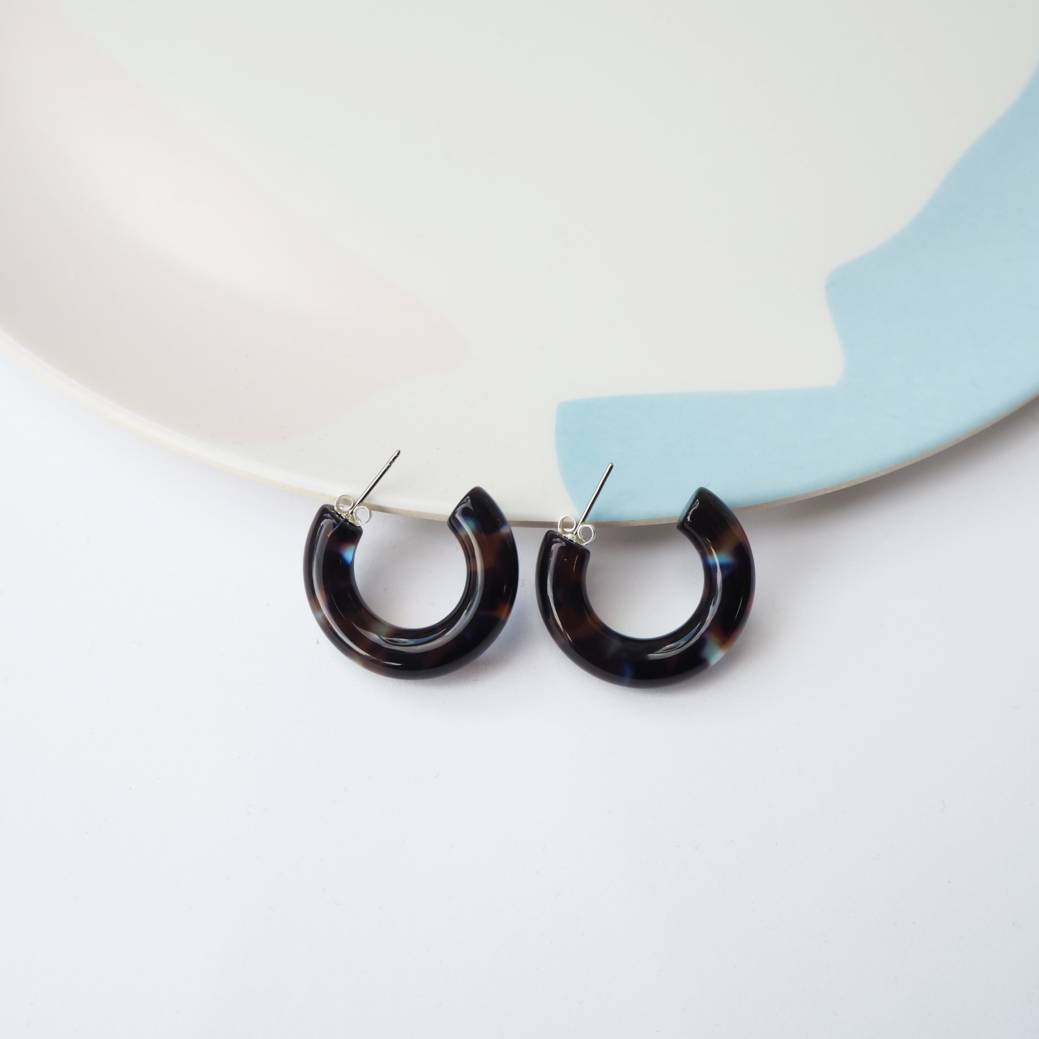 Pair of dark tortoiseshell hoop earrings with silver posts.