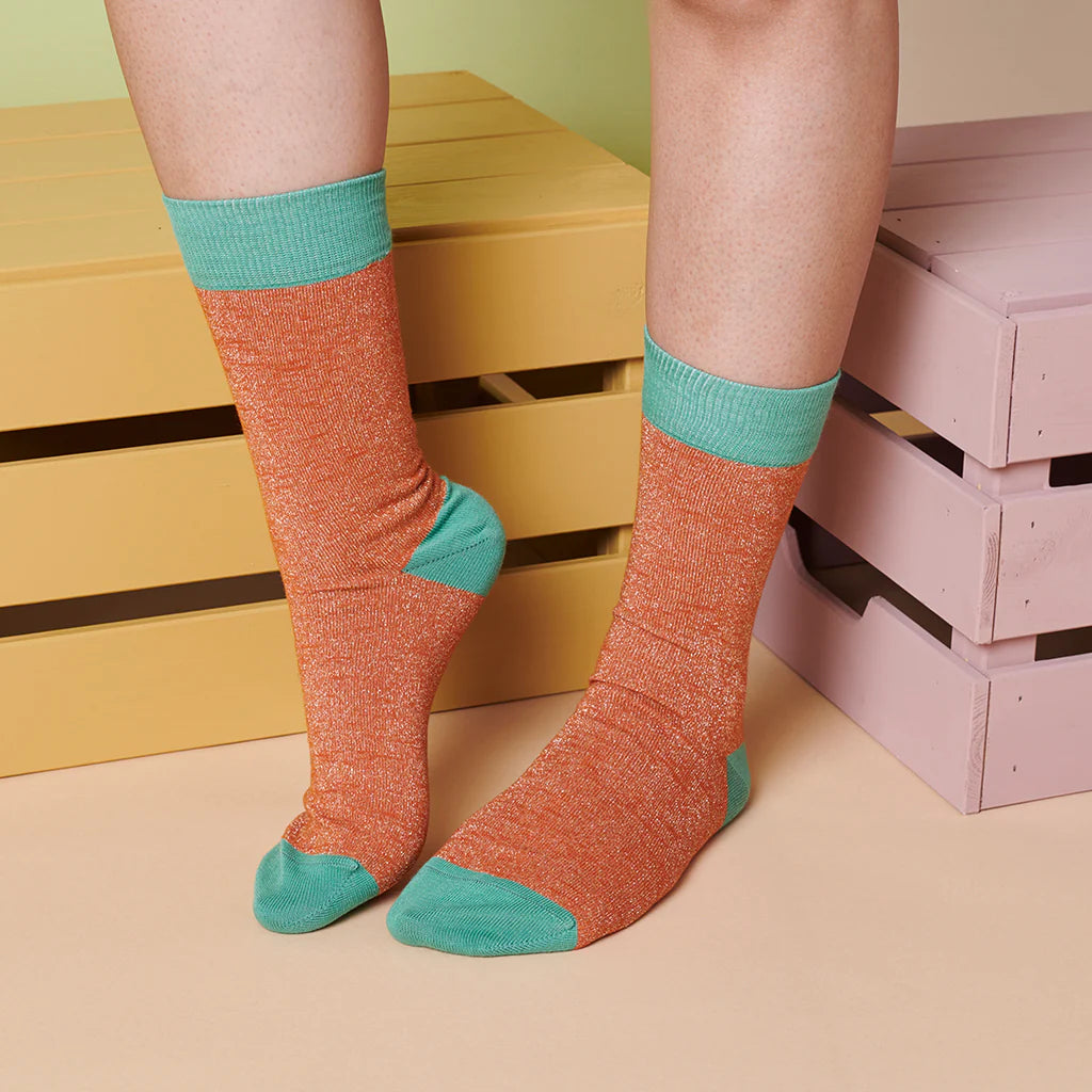 Pair of sparkly orange socks with teal cuffs.