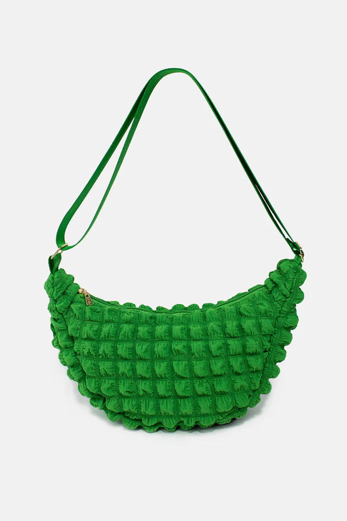 Bright green quilted crossbody bag with a half-moon shape and ruffled edges.