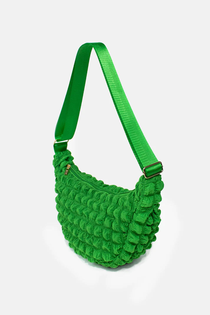 Bright green textured crossbody bag with a curved silhouette and adjustable shoulder strap.