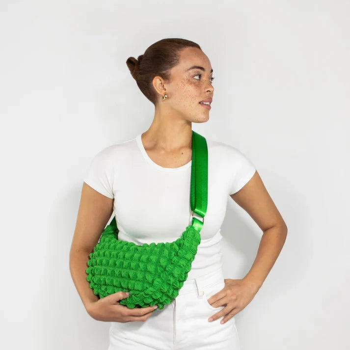 Bright green textured crossbody bag with a curved shape and a lime green strap.
