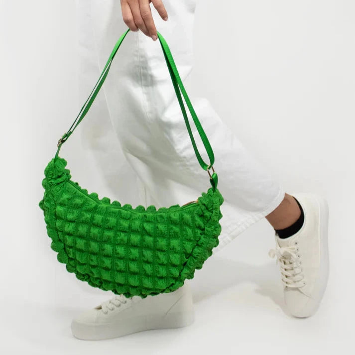 Bright green quilted crescent-shaped shoulder bag with a textured fabric.