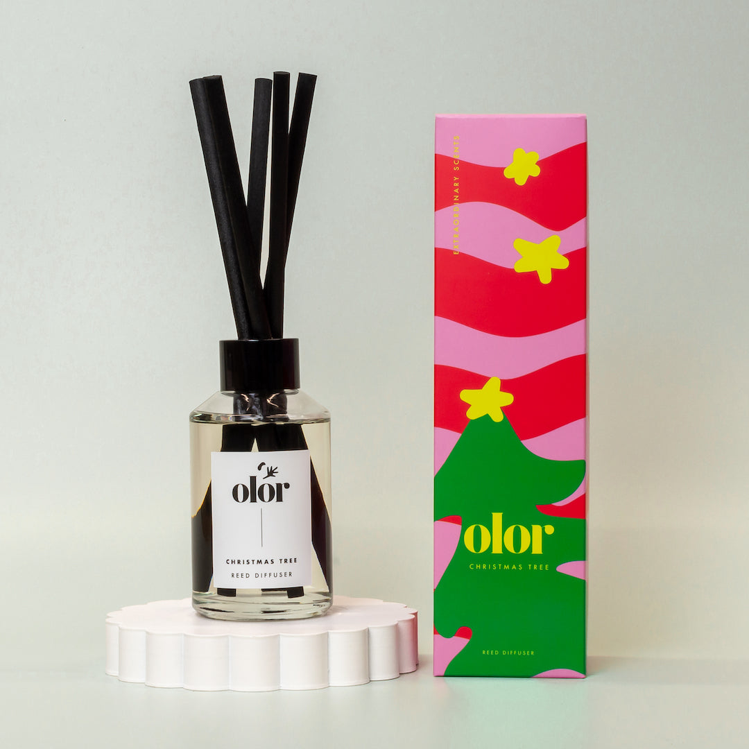 Olor Christmas Tree reed diffuser in clear glass bottle with black reeds and festive packaging.