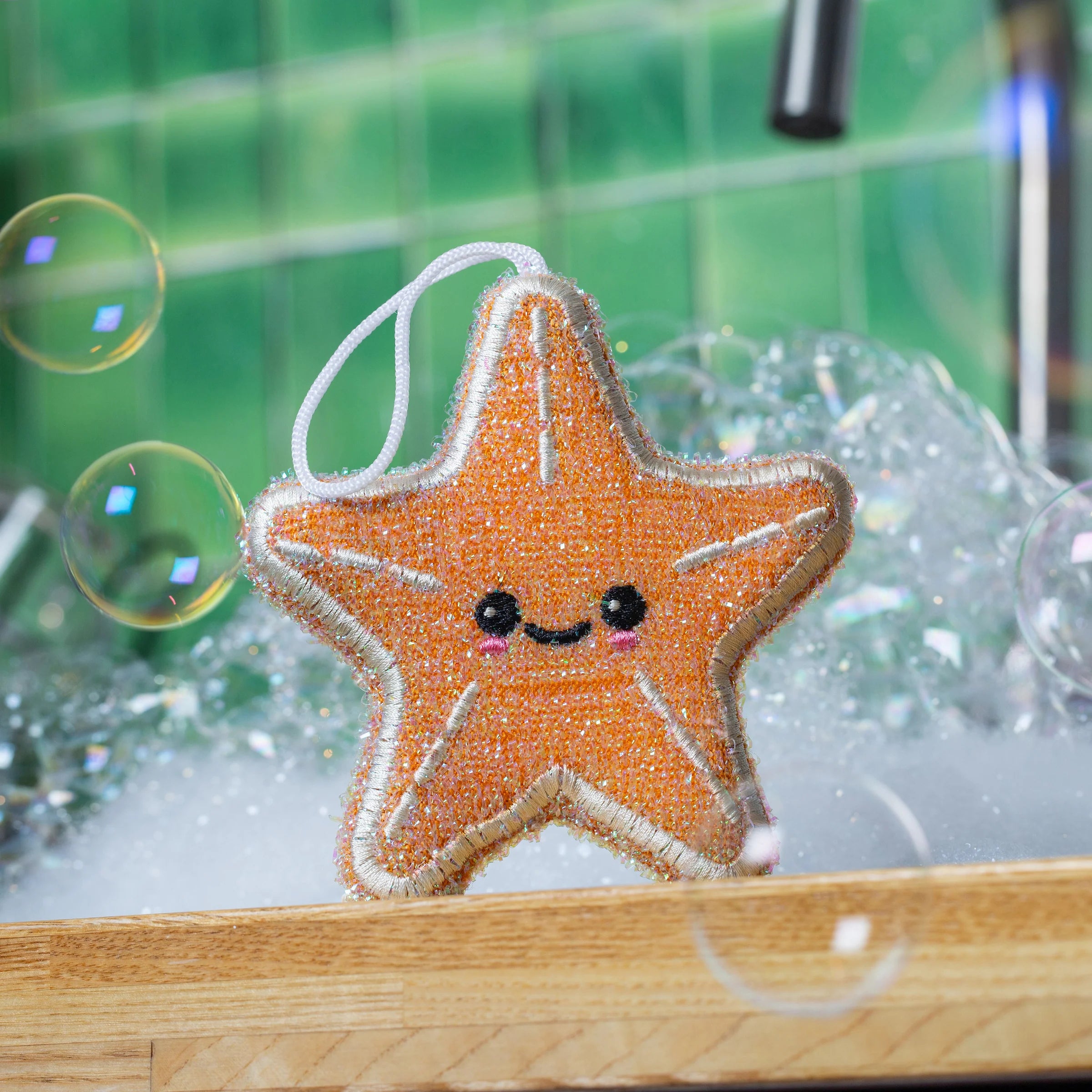 Star-shaped ornament with a smiling face on a wooden surface with bubbles and a green background