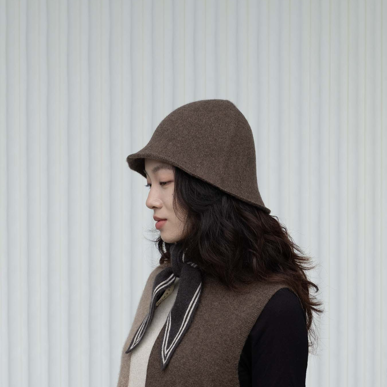 Woman wearing a brown felt hat and vest against a white background