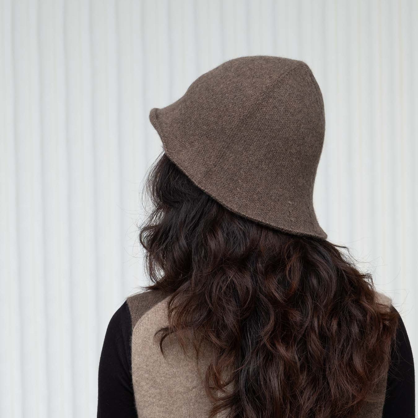 Person wearing a brown bucket hat with a neutral background