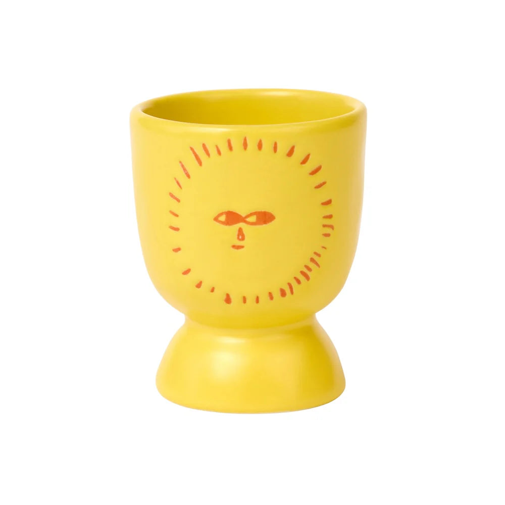 Yellow ceramic cup with a sun design on a white background
