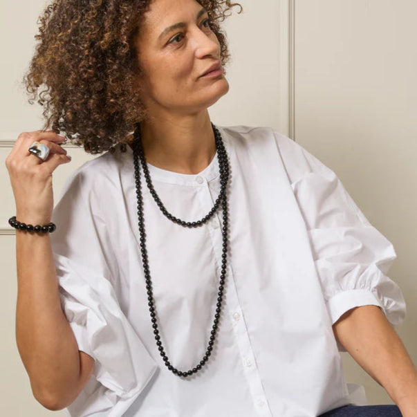 Double strand black beaded necklace.  The necklace is long and features uniform, dark beads.