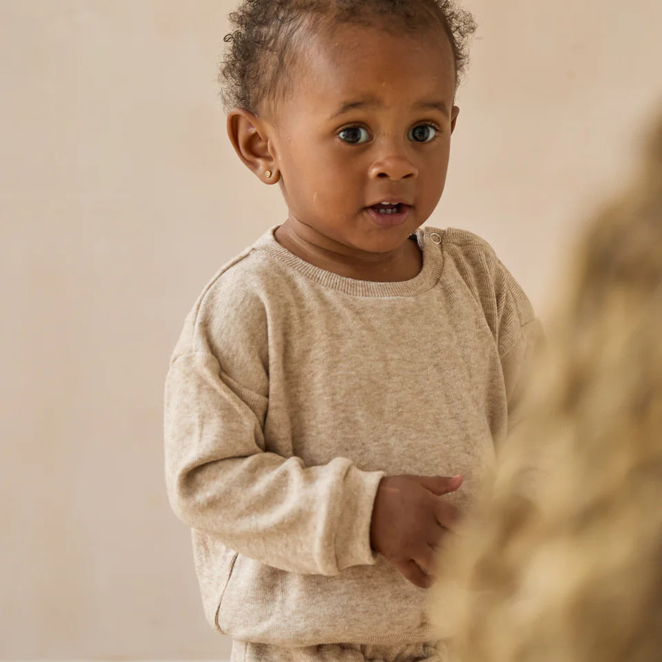 Child wearing a beige sweater against a neutral background