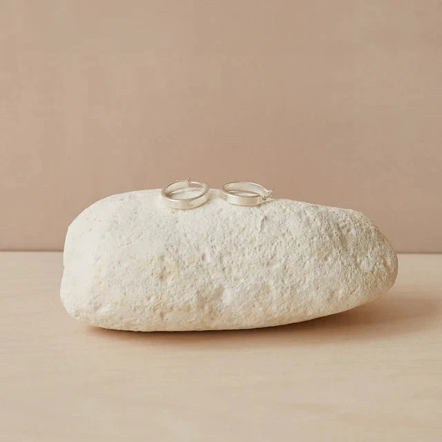 Two silver rings resting on a textured white stone, set against a soft beige background. Chalk UK branding featured.