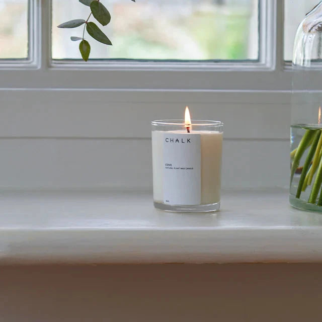 Lit Chalk Cove natural plant wax candle in a clear glass jar with a minimalist label.