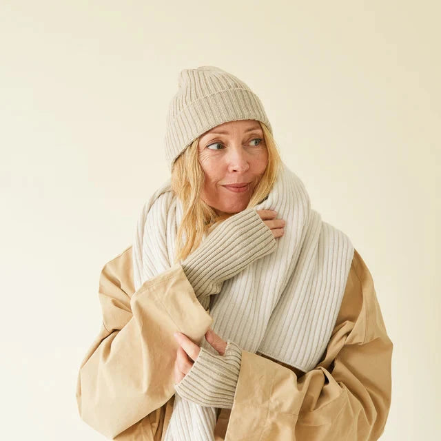 Beige ribbed knit beanie, scarf, and fingerless gloves.
