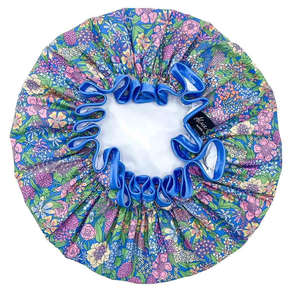 Floral shower cap with blue satin trim. Features a vibrant, multicolored floral print on a blue background.