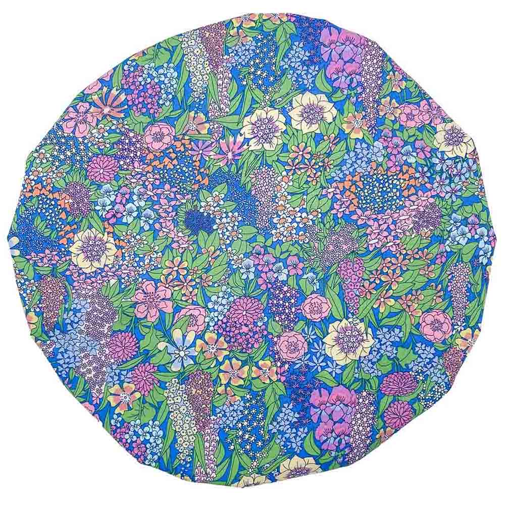 Round floral shower cap in vibrant blue with a densely packed pattern of pink, purple, yellow, and white flowers.