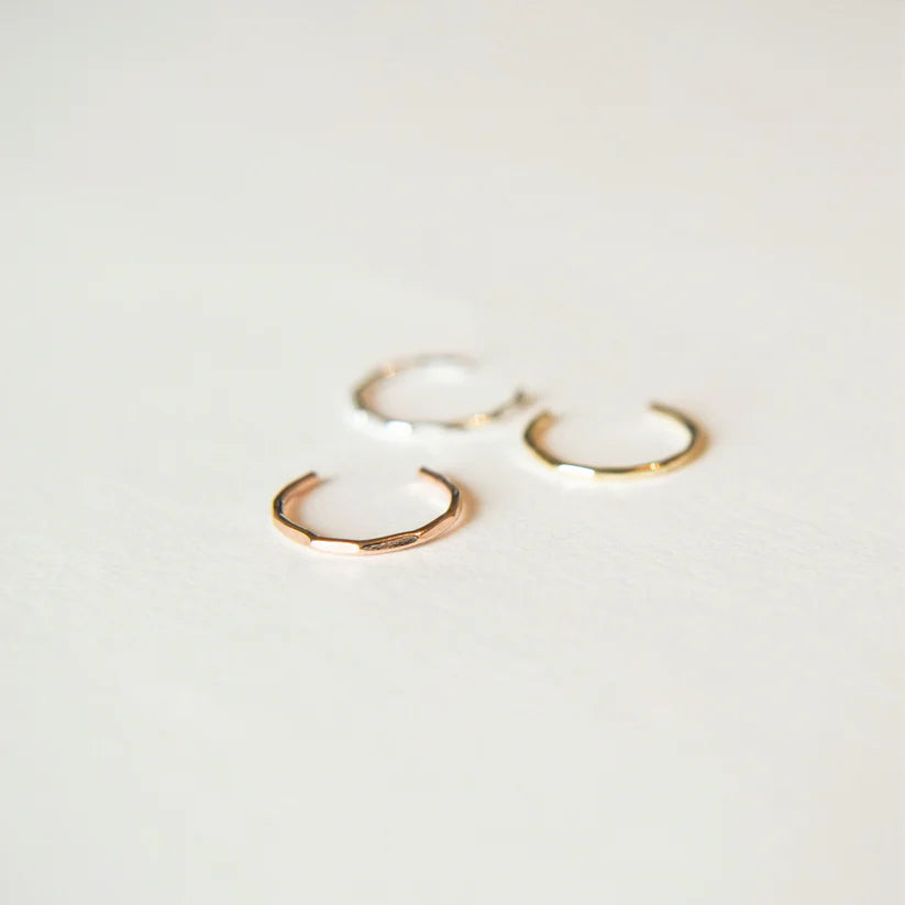 Three hammered metal ear cuffs in rose gold, silver, and gold.