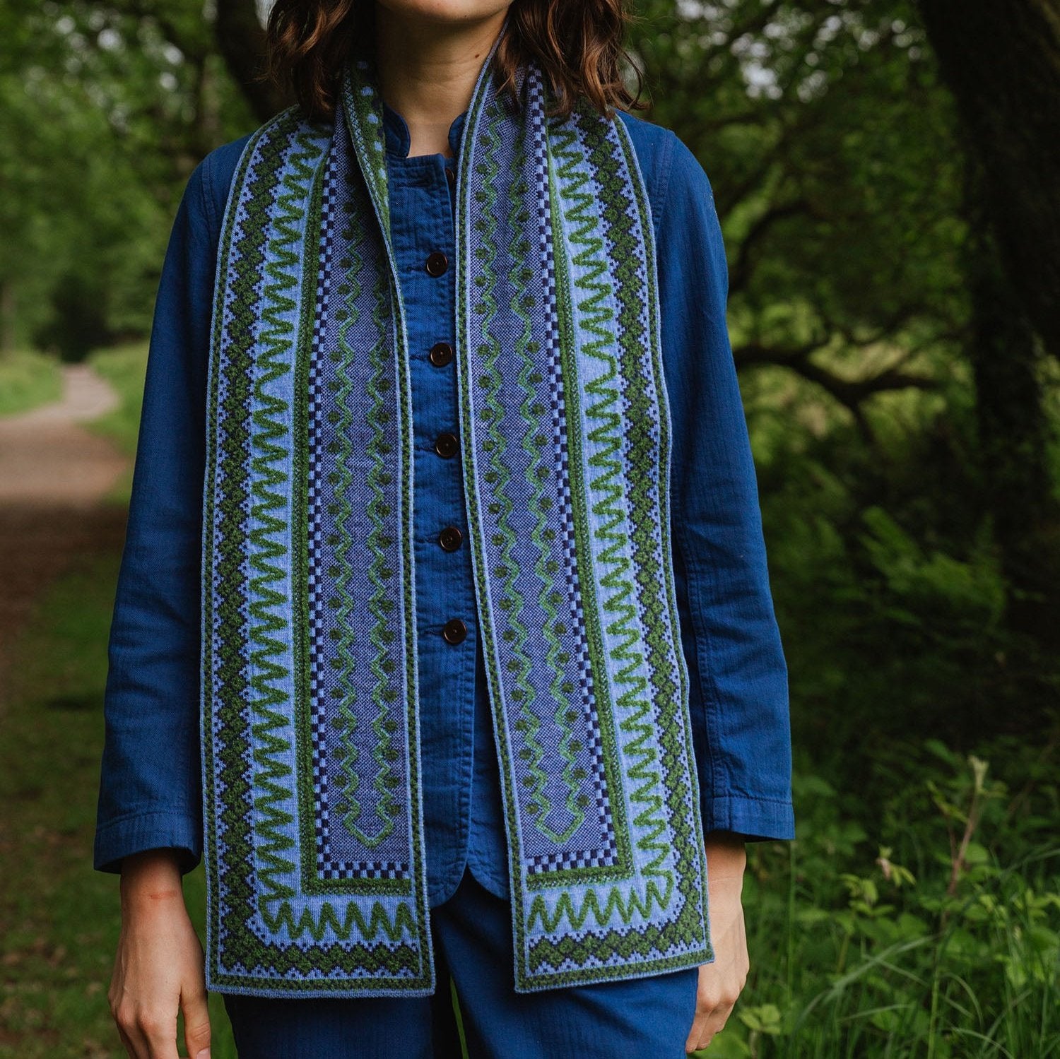 Blue and green patterned woven scarf with intricate embroidered border details.