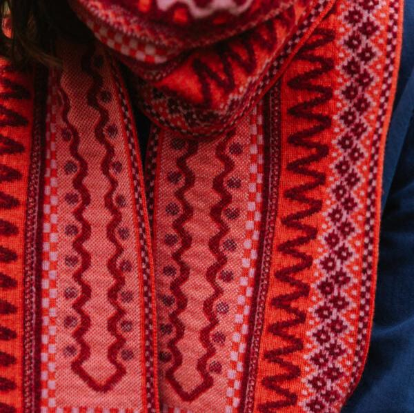 Red wool scarf with intricate woven pattern in shades of pink and maroon.