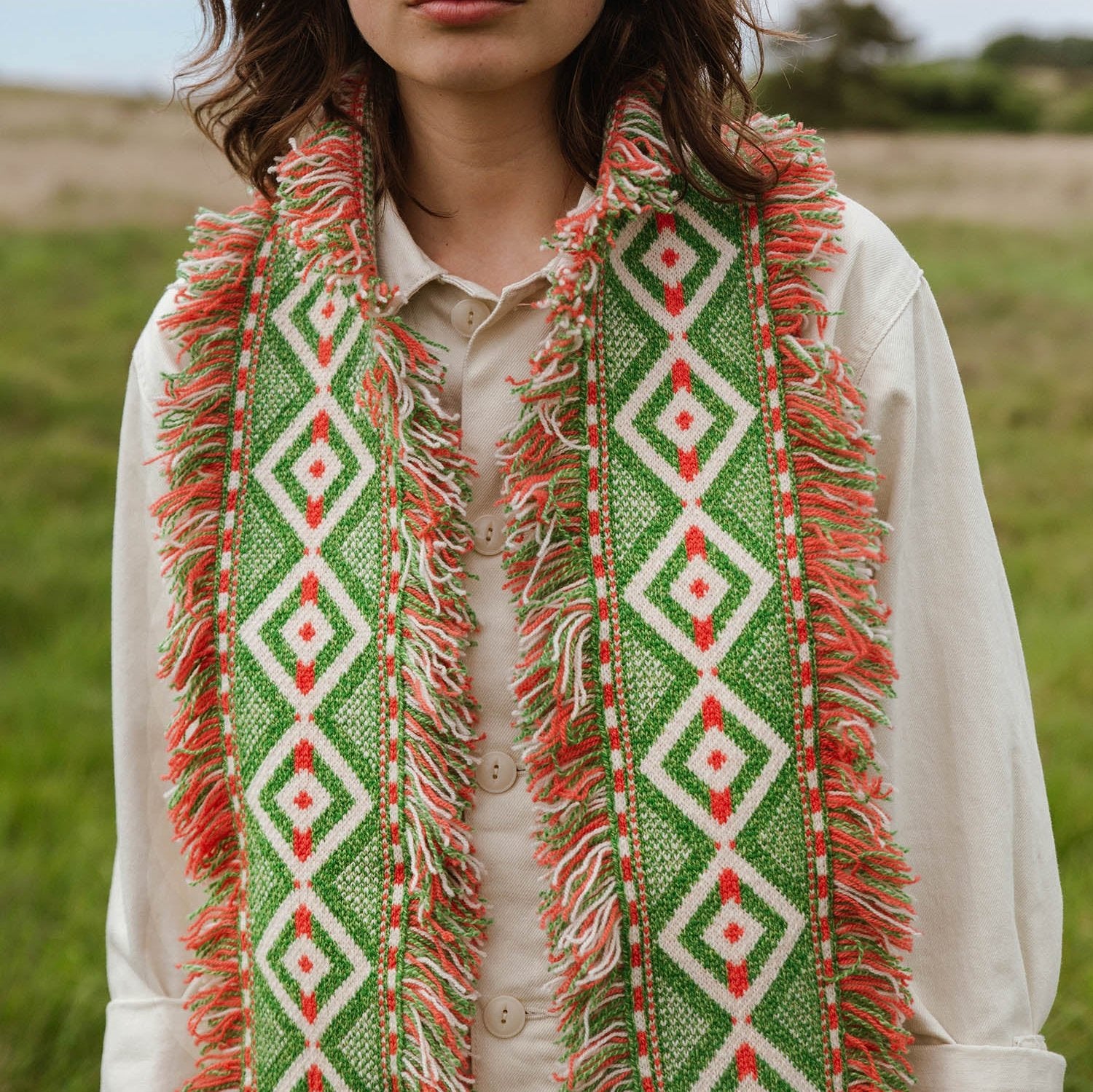 Green and coral fringed scarf with a geometric diamond pattern.