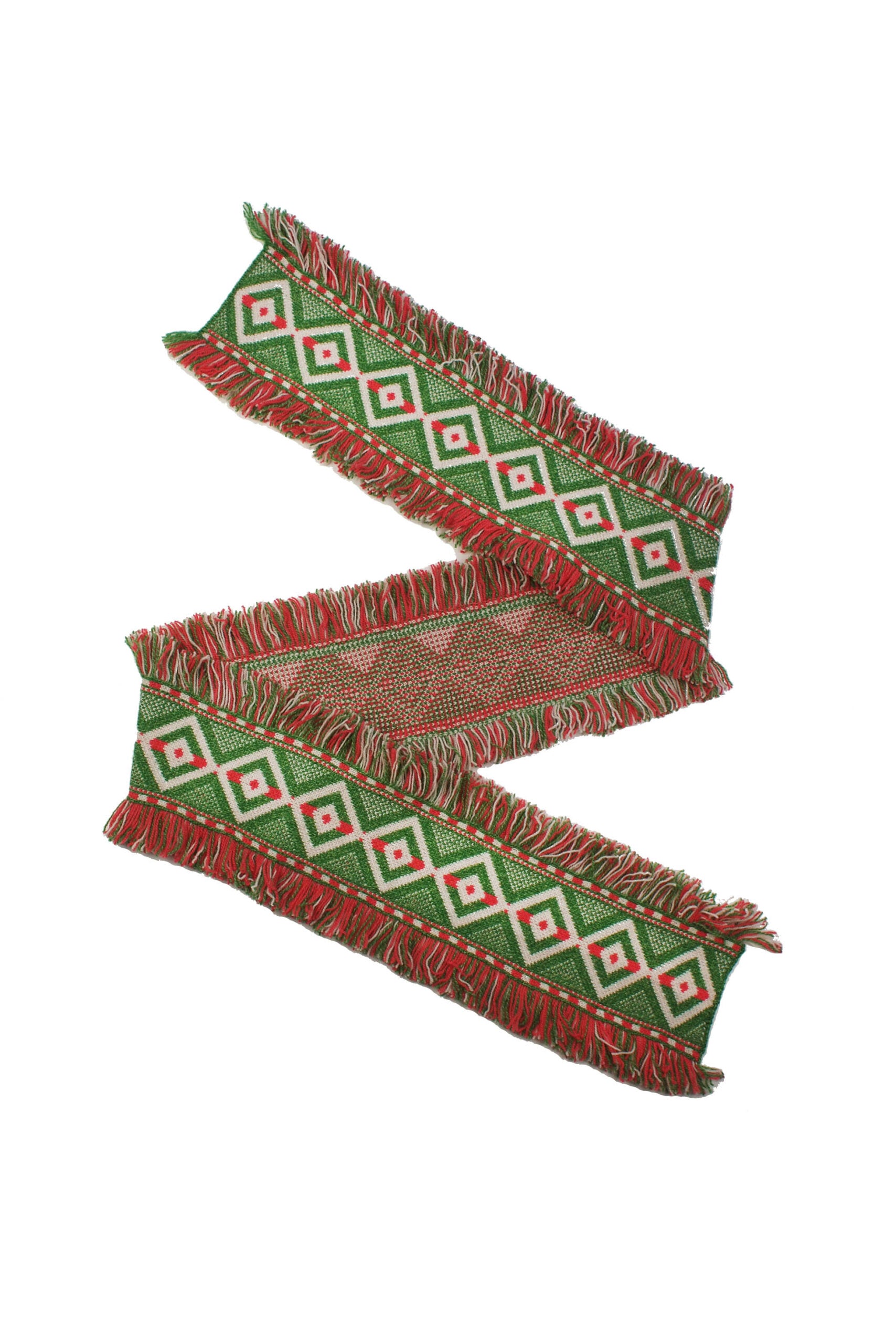 Woven textile with green, red, and white geometric pattern and fringed edges.