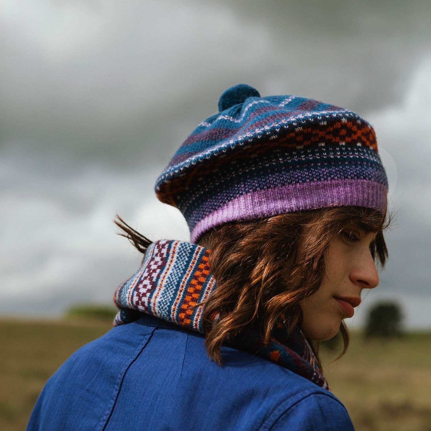 Fair Isle patterned wool beret with purple band, worn with matching patterned scarf.