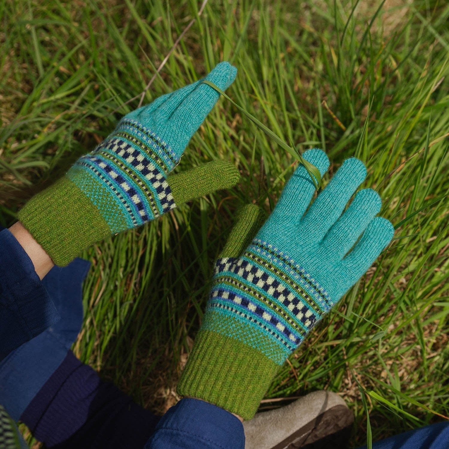 Pair of teal and olive green wool gloves with a colorful Fair Isle pattern.