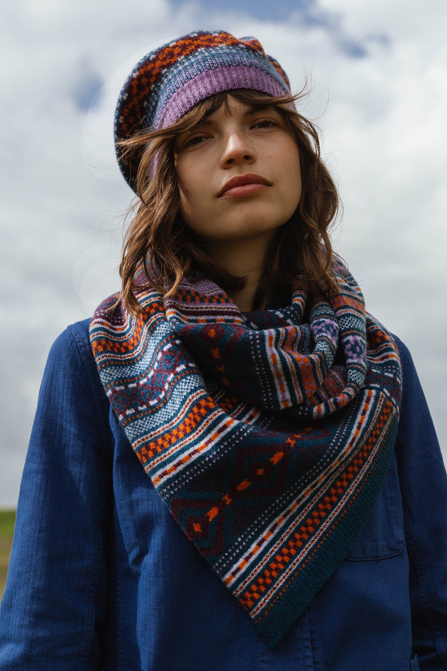 Woman wearing a teal, orange, and purple patterned knit scarf and matching knit beret.