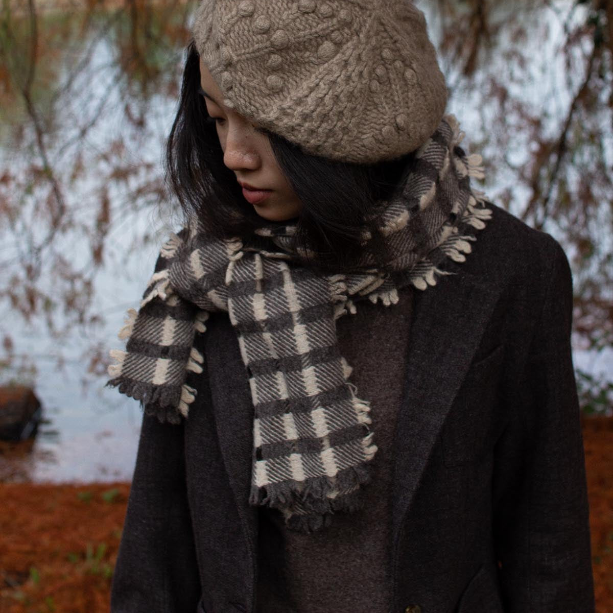 Person wearing a knitted hat and plaid scarf in a snowy outdoor setting