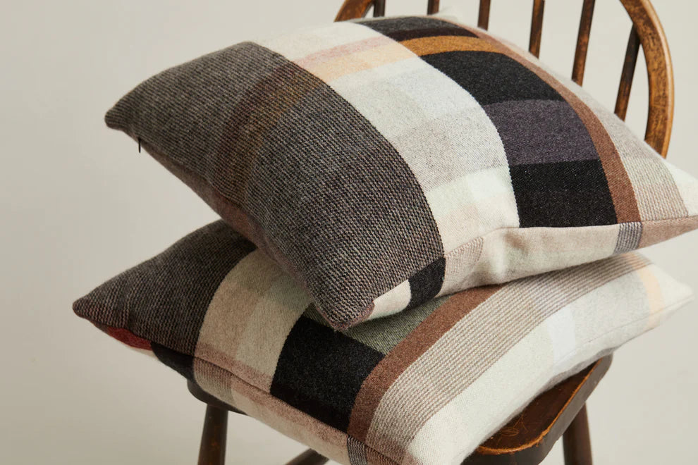 Plaid patterned cushions on a wooden chair against a neutral background