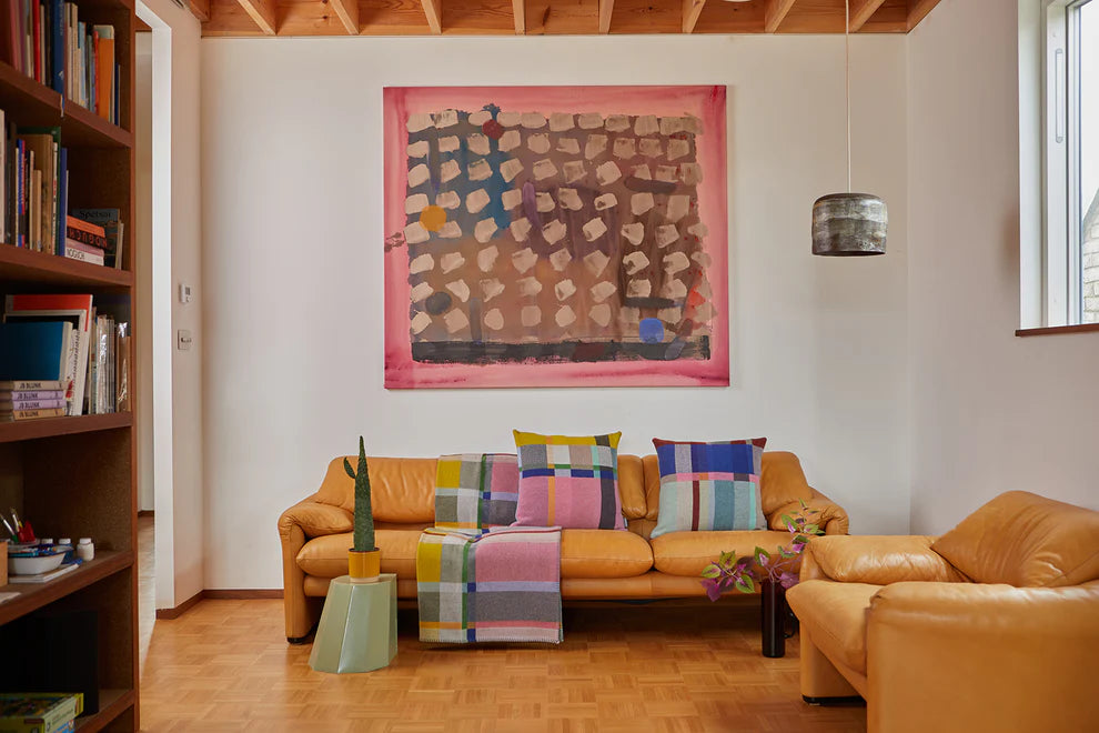Living room with orange sofa, colorful cushions, and abstract painting on wall.