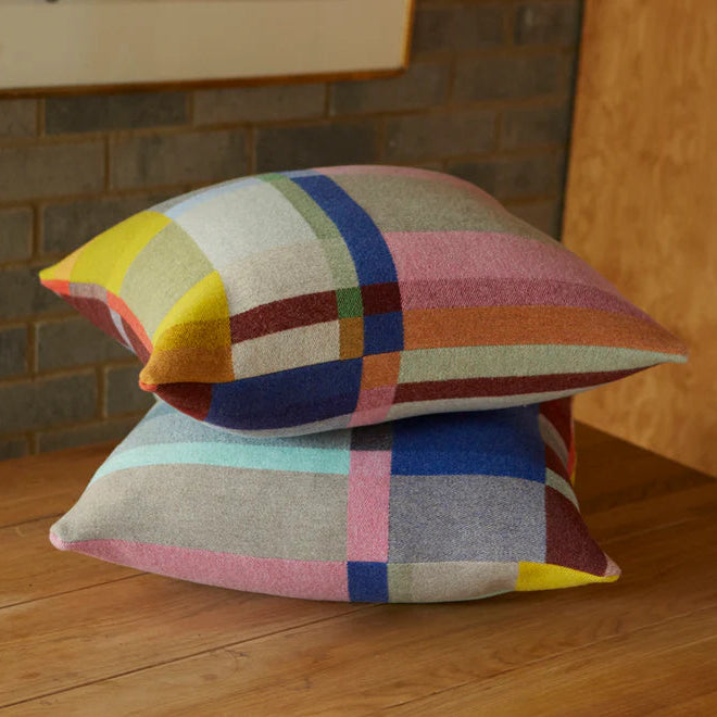 Colorful checkered pillows on a wooden floor with a brick wall background