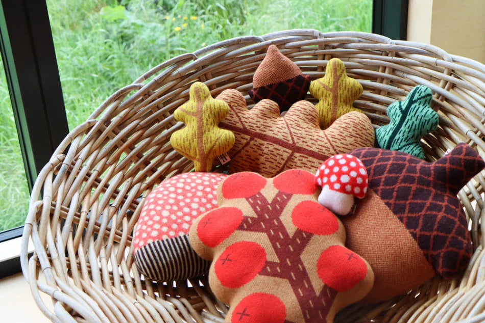 Collection of fabric animals including a bear, acorns, and a mushroom in a woven basket.
