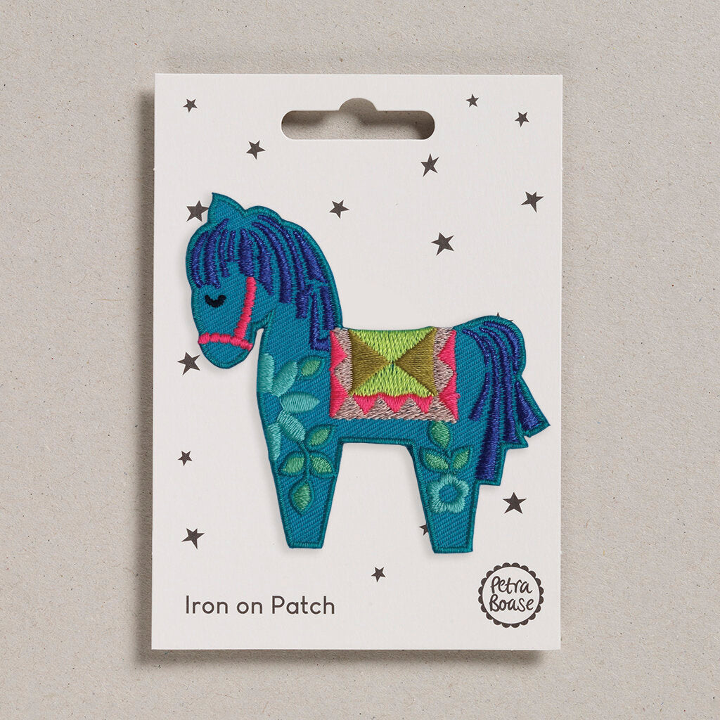 Teal embroidered iron-on patch depicting a stylized horse with floral details and a patterned saddle.