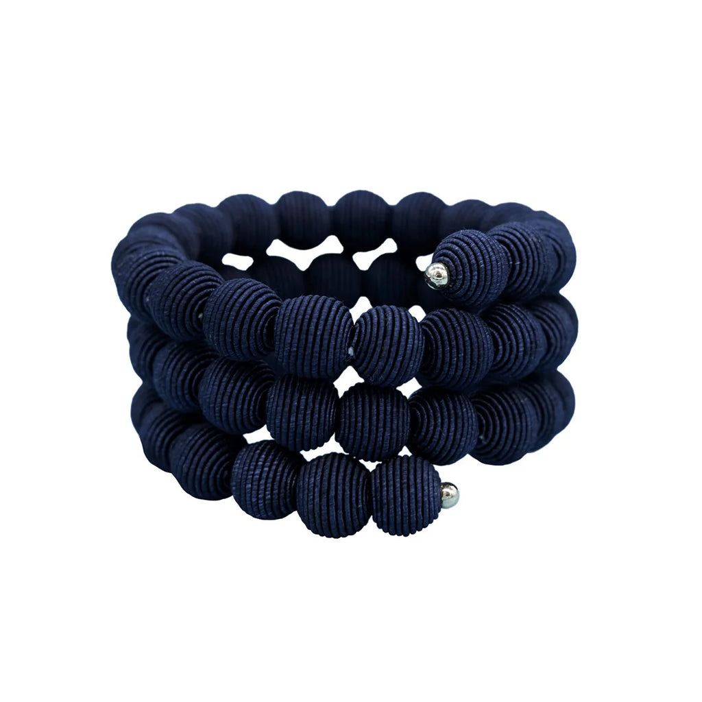Navy blue fabric beaded bracelet; three rows of textured spherical beads spiral around.