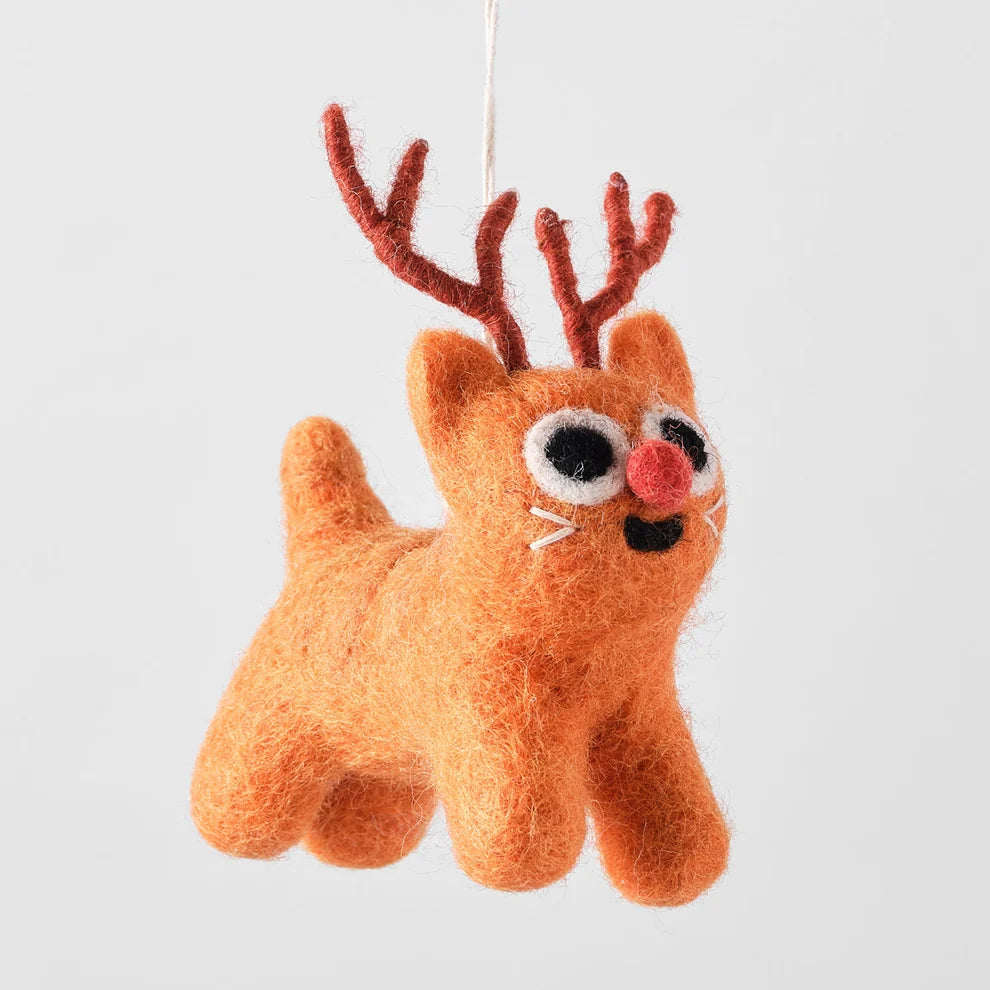 A felted wool Christmas ornament shaped like a playful orange kitten with red antlers, large black-and-white eyes, and a pink nose, hanging against a plain light gray background.